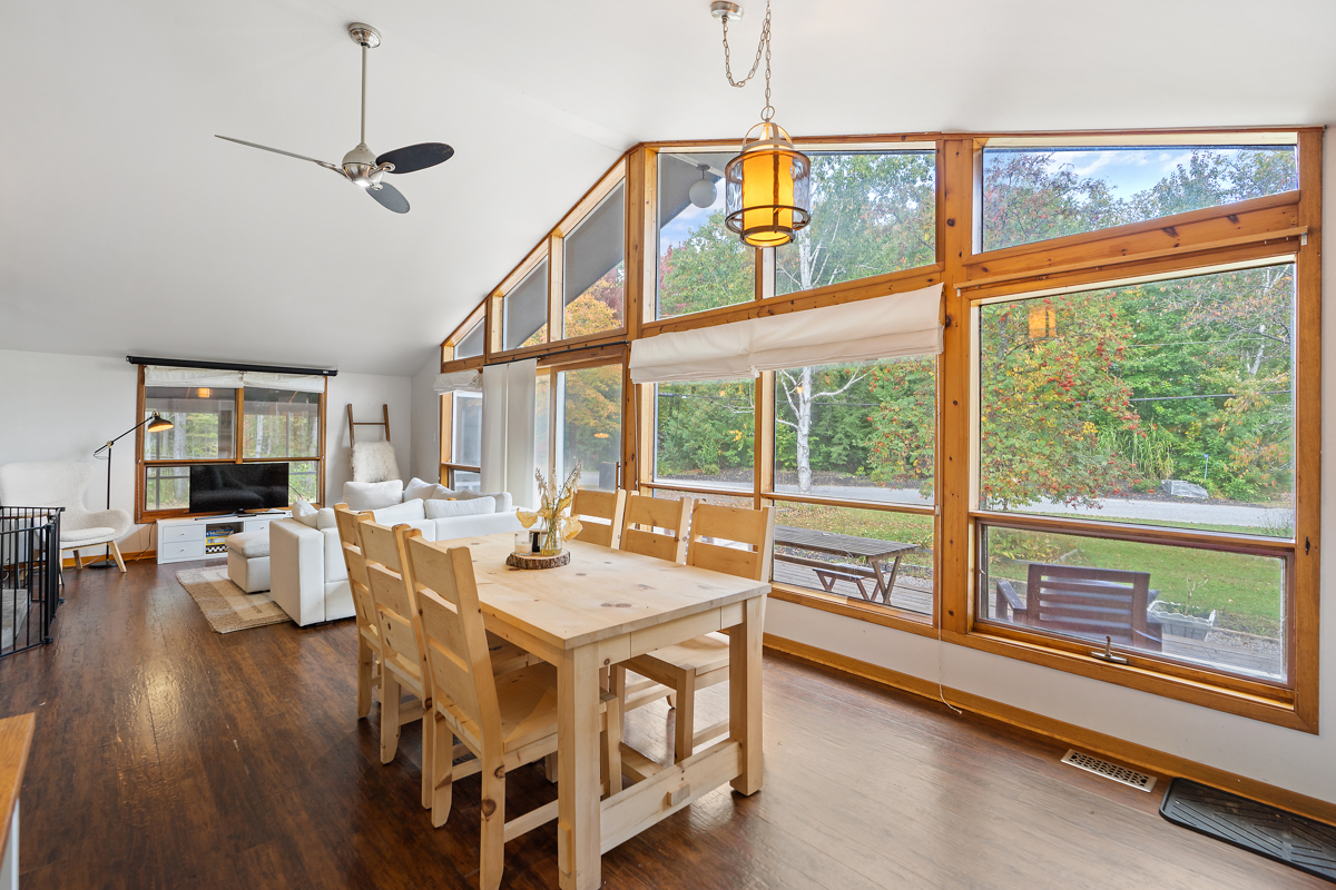 A main floor bungalow space that flows from the dining area to the living area. Floor-to-ceiling windows span the front wall of the house.