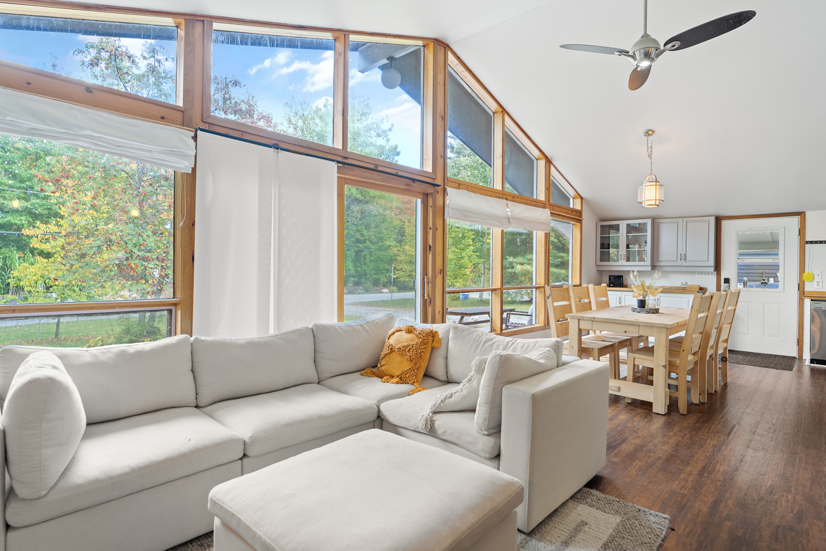 A bright, main floor bungalow space that flows from the living area to the dining area. Floor-to-ceiling windows span the front wall of the house.