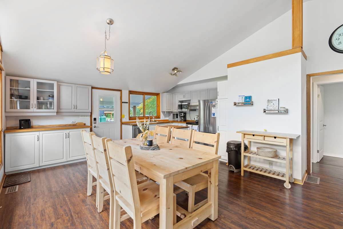 A dining table and chairs sits in front of a small kitchen area.