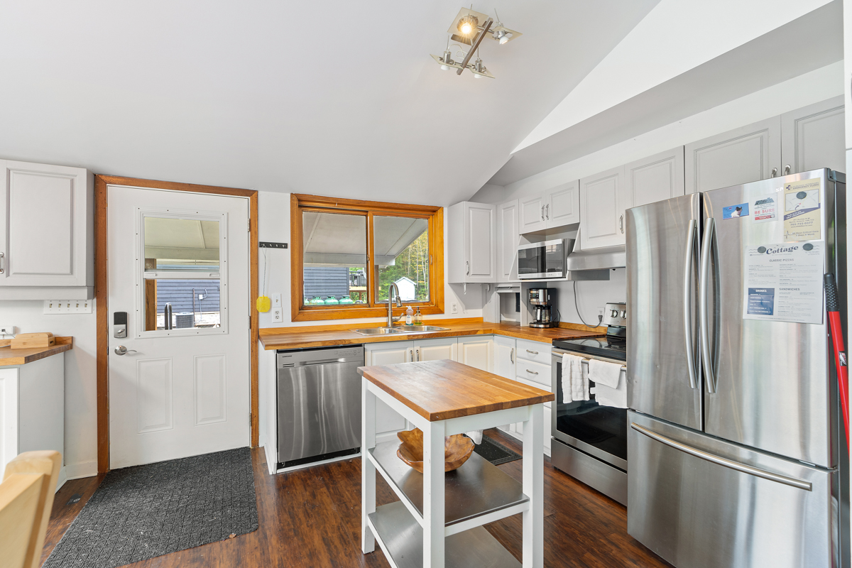 Inside a doorway that leads to a small kitchen with stainless steel appliances and an island.