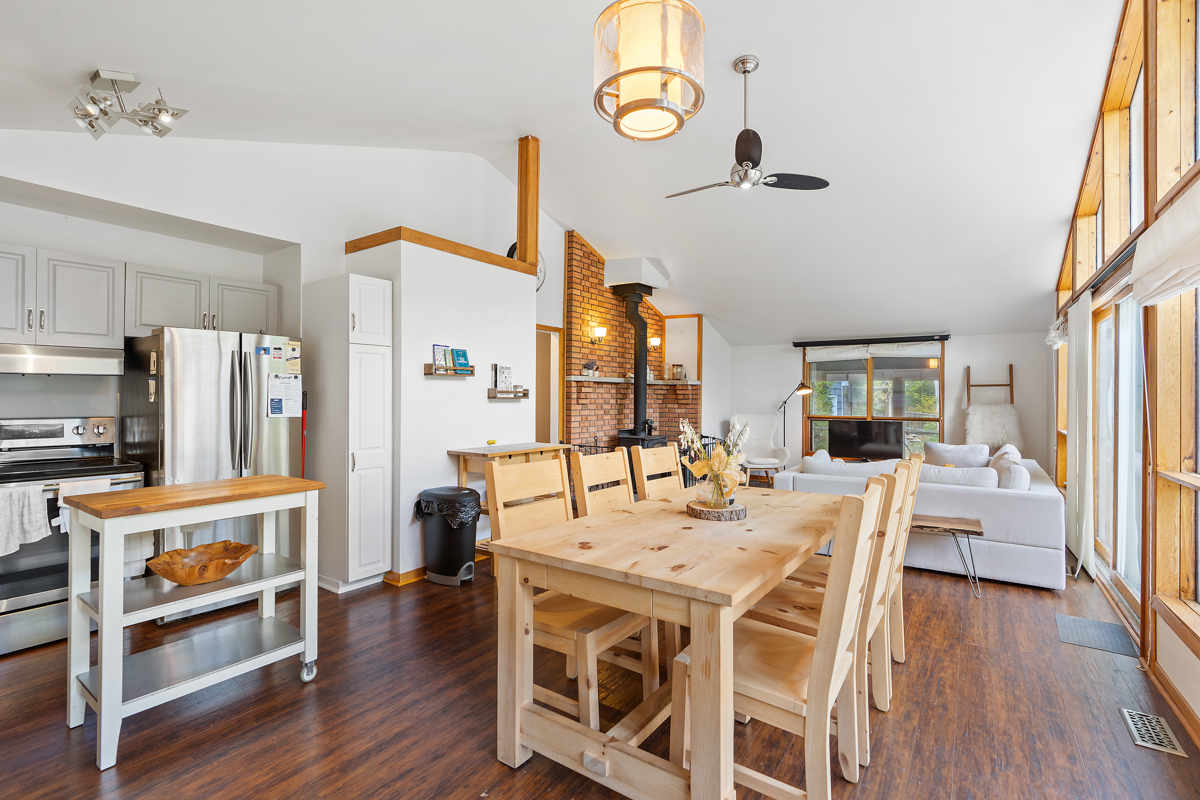 A dining room table and chairs sits in front of a small kitchen.