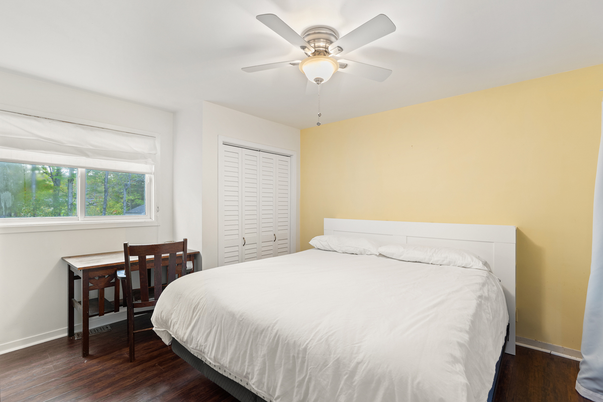 A bedroom with one yellow wall, a big bed, and a closet.