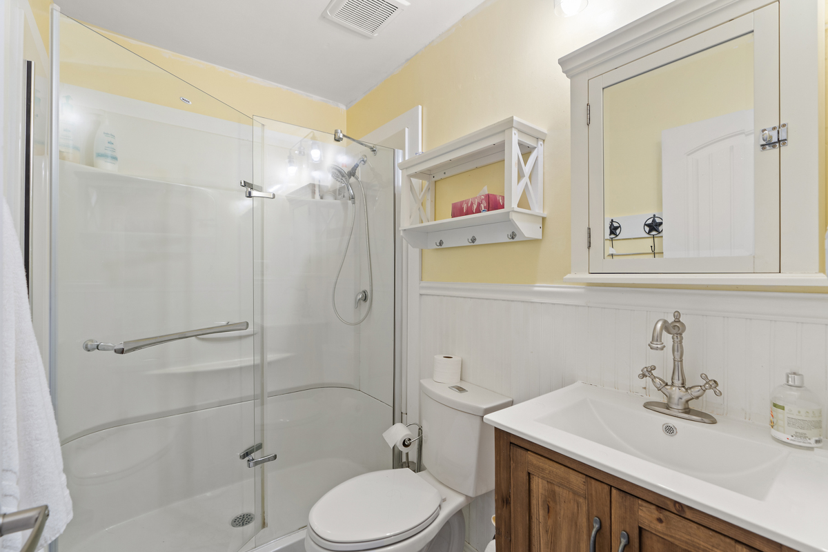 A three-piece bathroom with a toilet, a sink, and a walk-in shower.