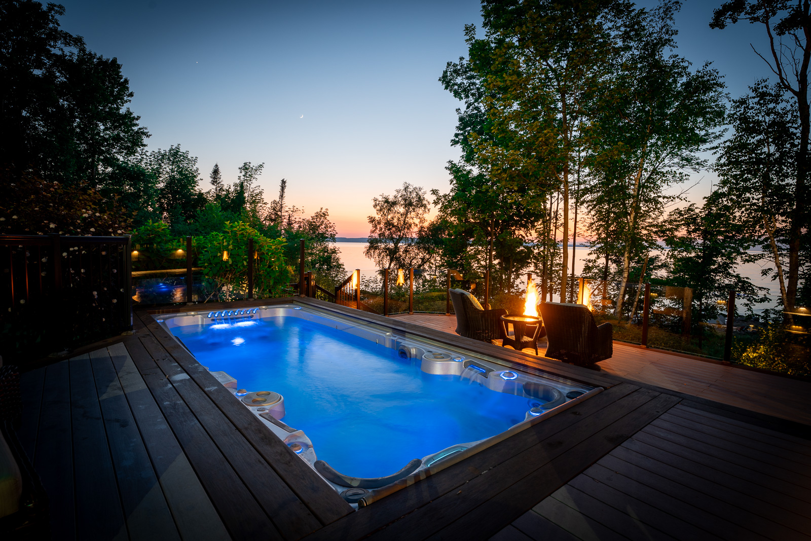 A long swim spa hot tub, lit up blue at night.