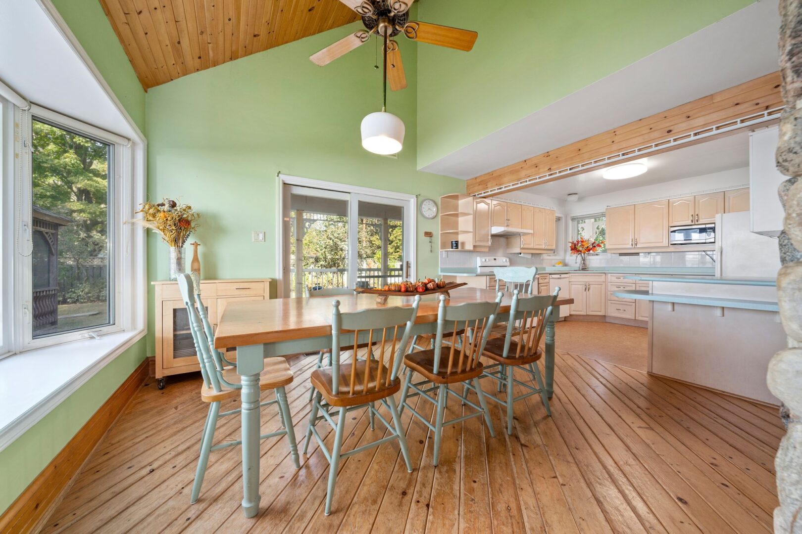 A dining area with light green walls, hardwood floors, and a table and chairs.