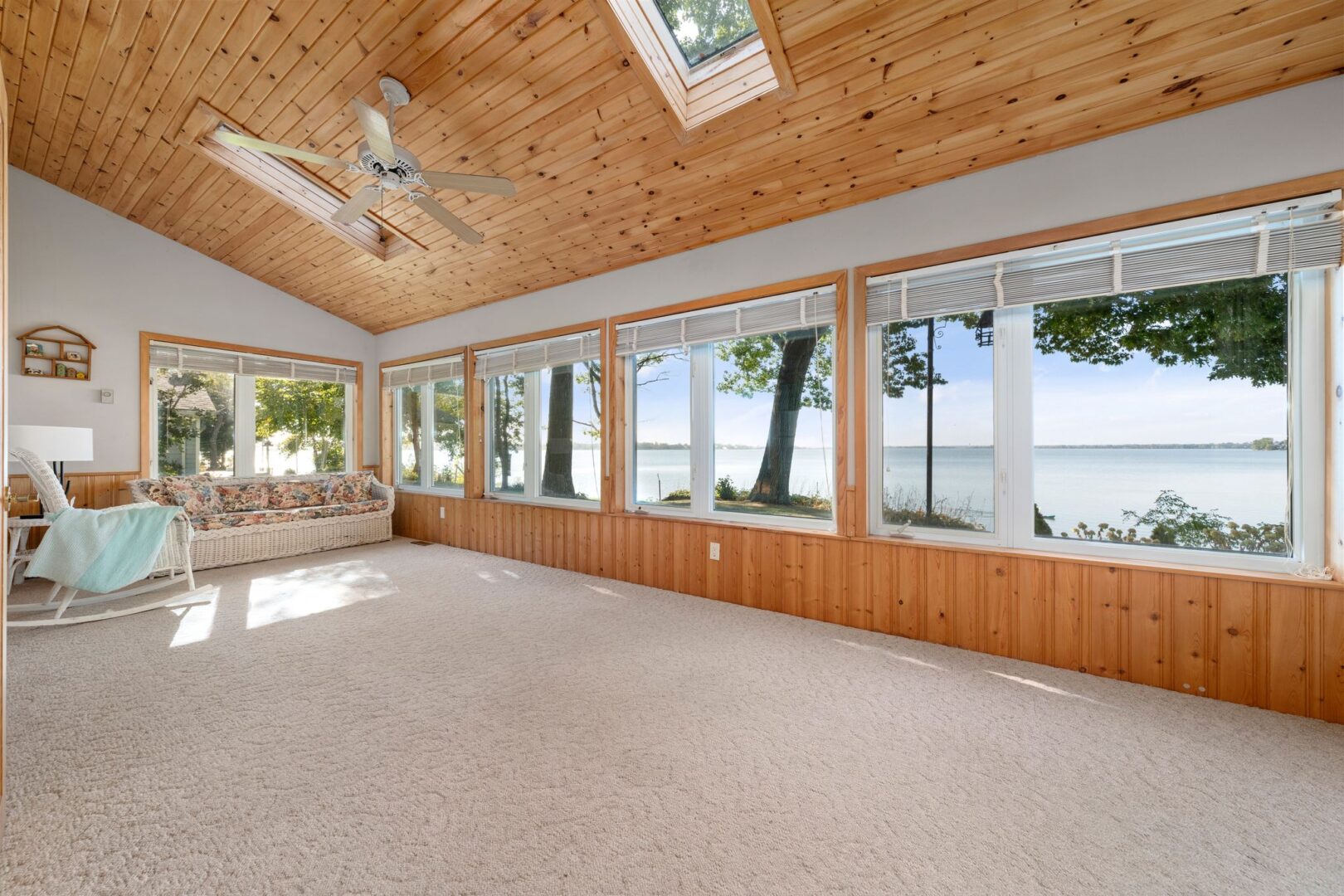 A big sunroom with lots of windows and wood-panelled walls and ceiling.