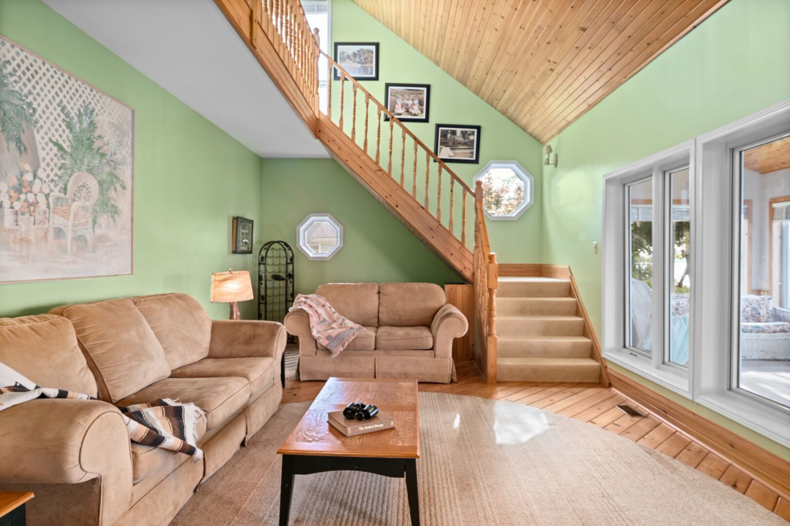 A bright living area with two couches, hardwood floors, and a staircase leading up to a second level.
