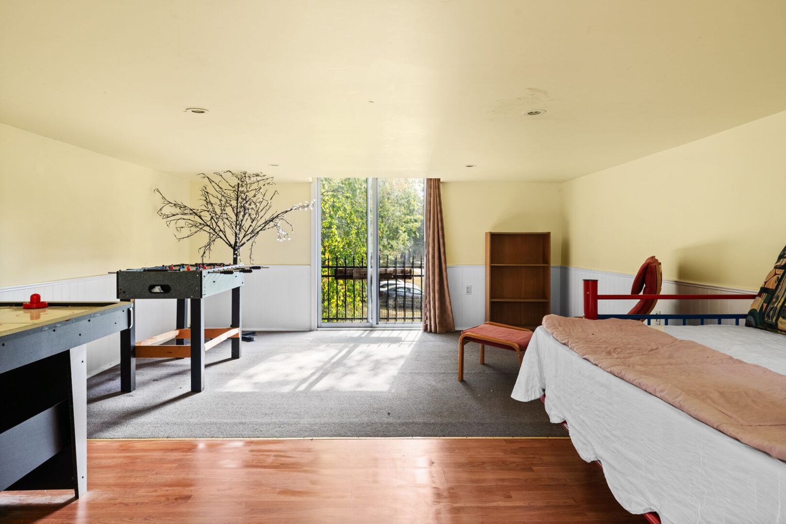 A bright loft space of a detached garage, with game tables and hardwood floors.