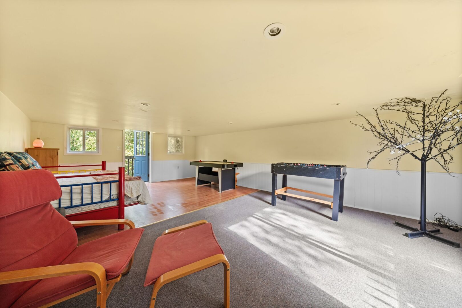 A bright loft space of a detached garage, with an air hockey table, a foosball table, and hardwood floors.