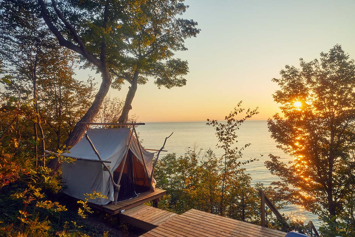 a tent overlooking treetops and a lake