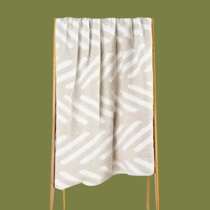 a white and cream patterned blanket on a green background