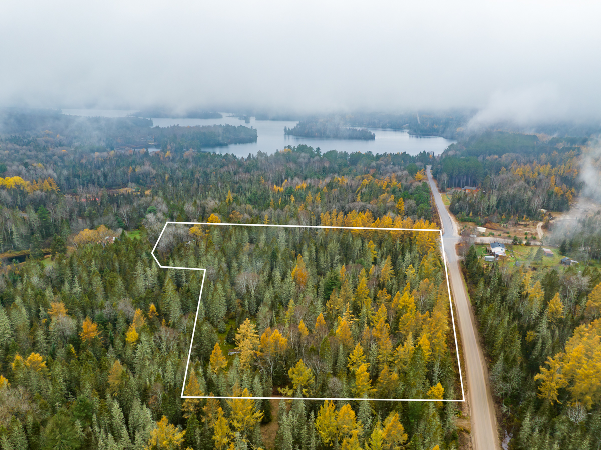 A large forested area close to a lake is bordered in white to indicate the property lines.