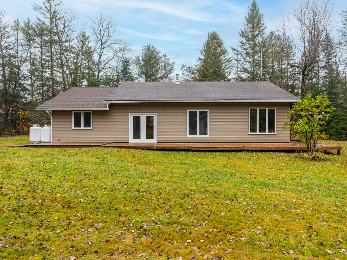 The long side of a bungalow-style home, with a double-door side entrance. The home sits on a large grassy yard.