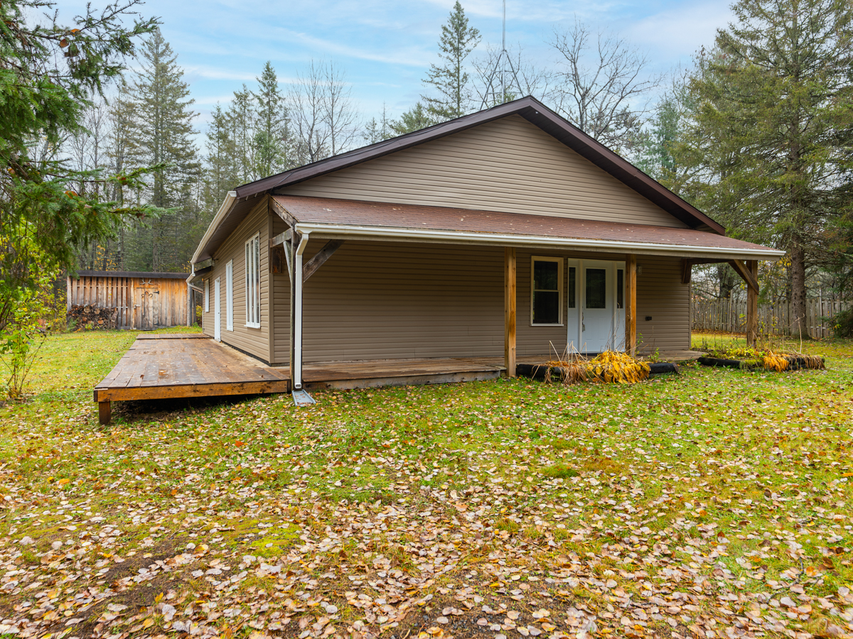 The front of a rural, bungalow-style home, with a wrap-around porch.