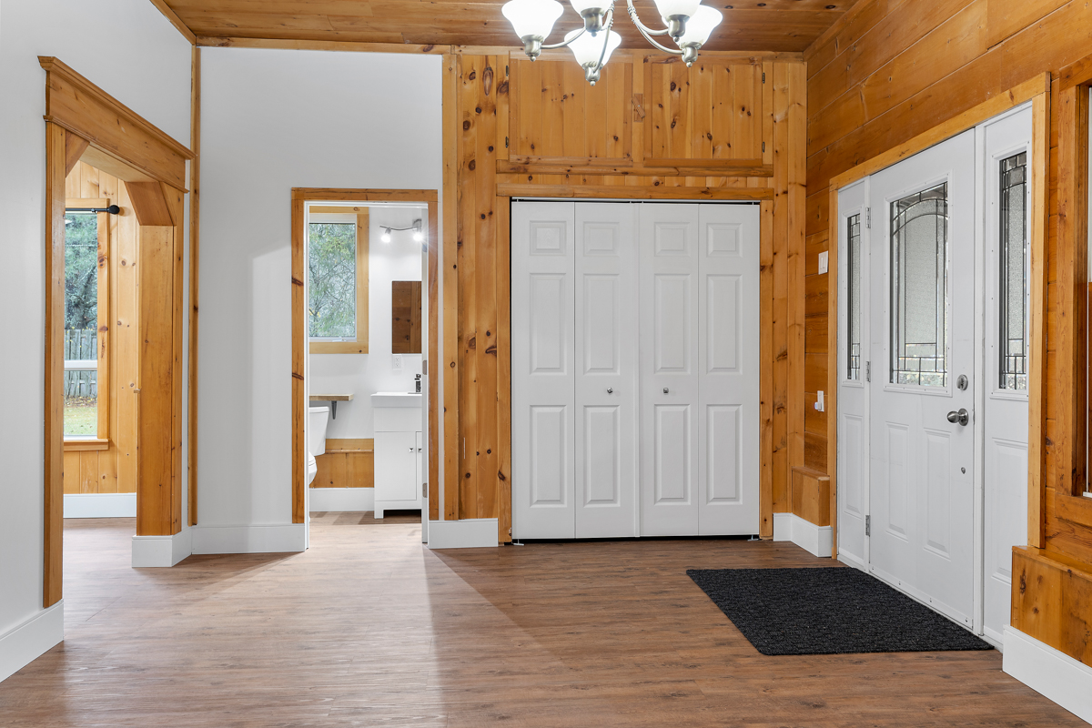 A bright, spacious front entrance area, with a bathroom just off the side. The ceiling and walls are wood-panelled.
