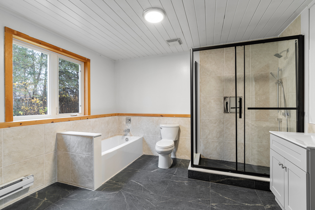 A large bathroom with a toilet, a bathtub, and a walk-in shower.