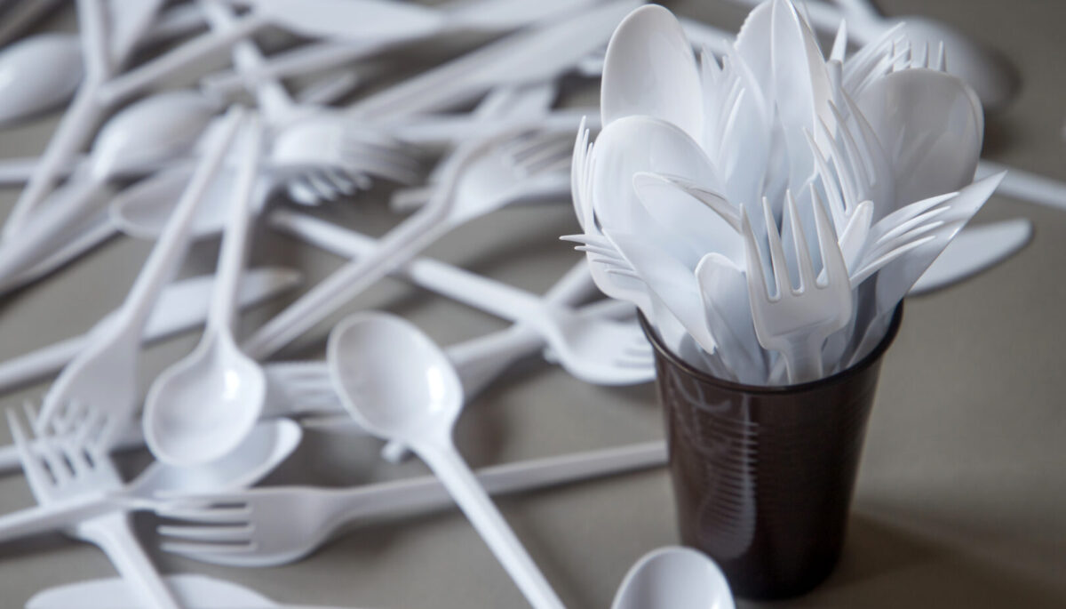 white plastic forks in a cup and spread out on a table