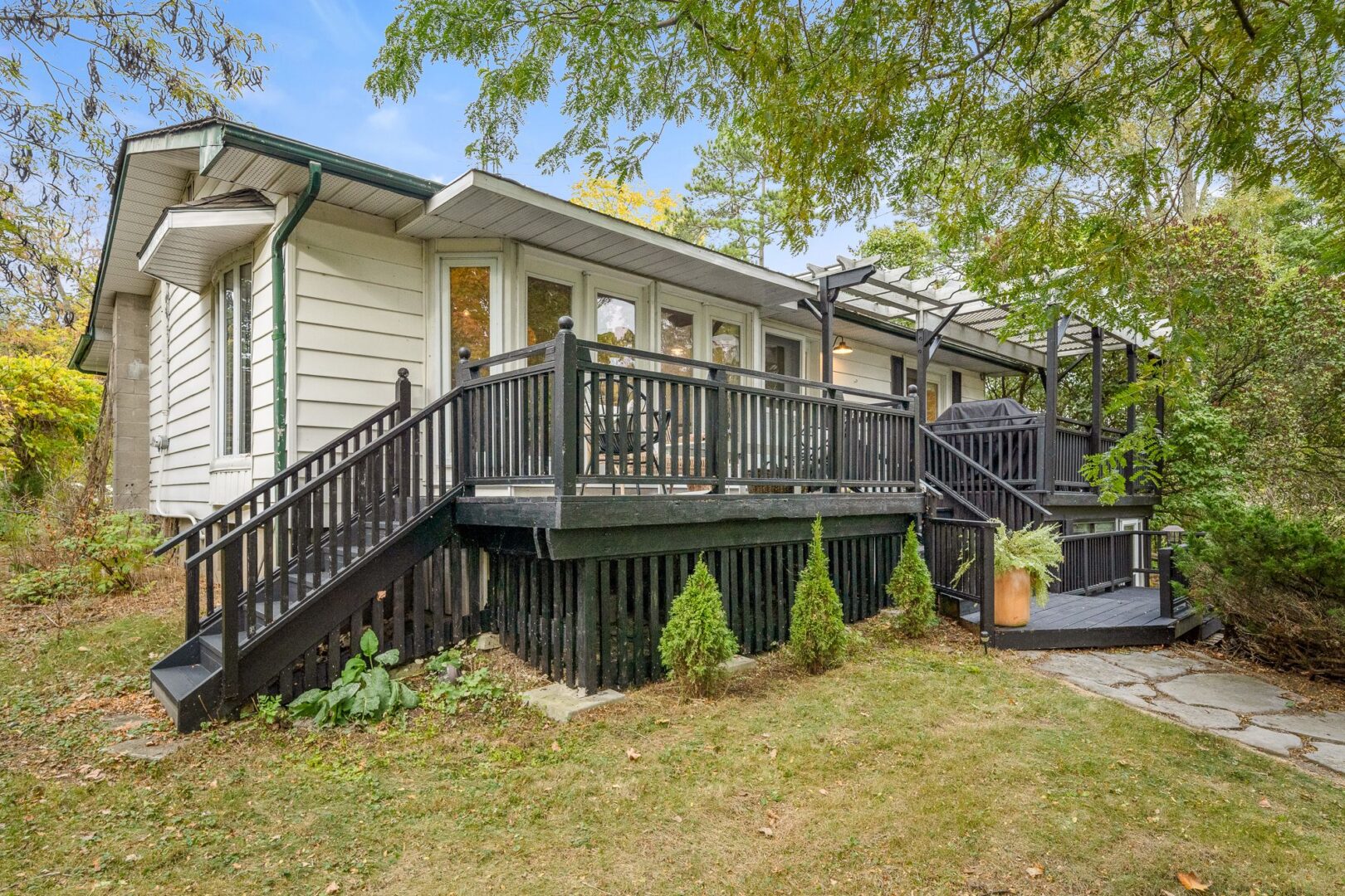 The front of a raised bungalow with stairs leading up to a dark-grey painted porch and the main entrance of the house.