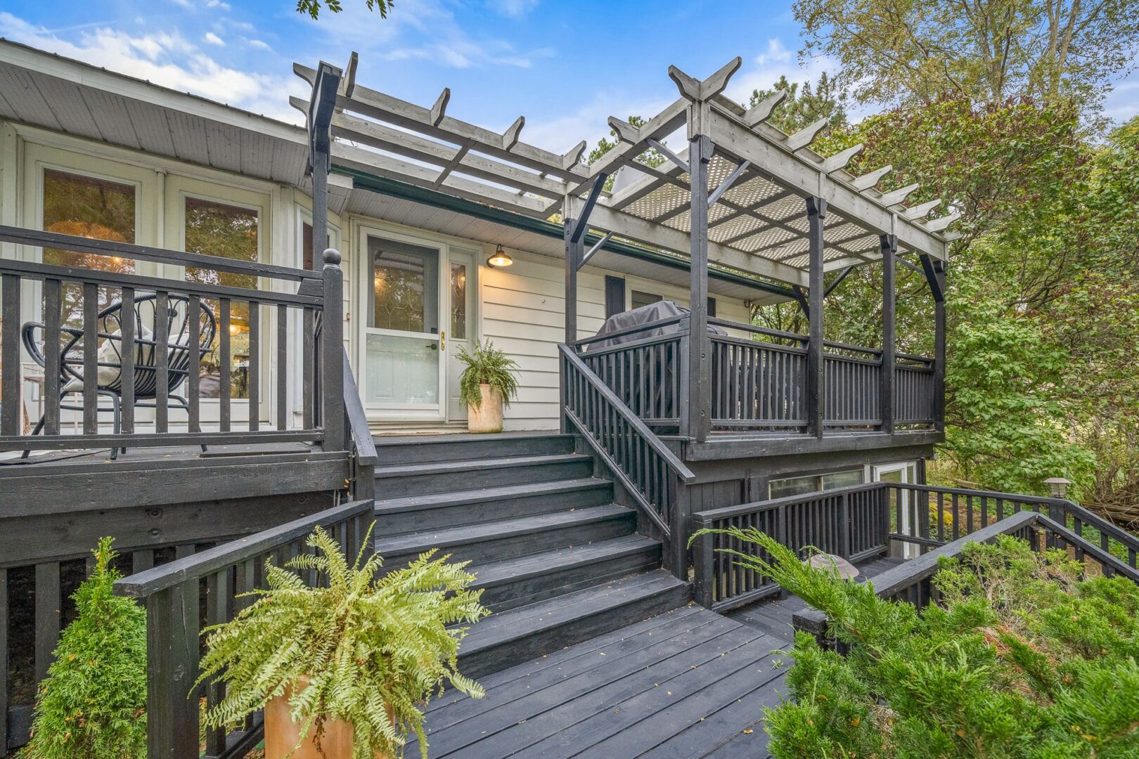 Stairs lead up to the front porch of a raised bungalow. The stairs and porch are painted a dark grey colour.