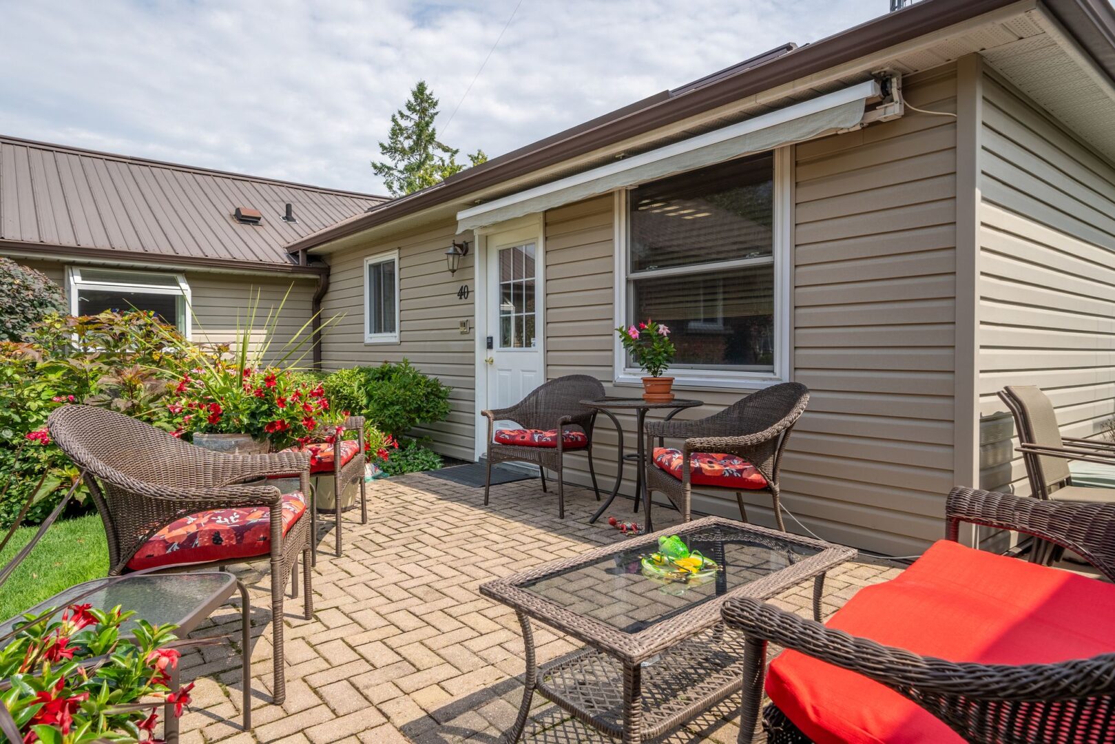 A patio with outdoor chairs and a table extends off the side of a big bungalow.