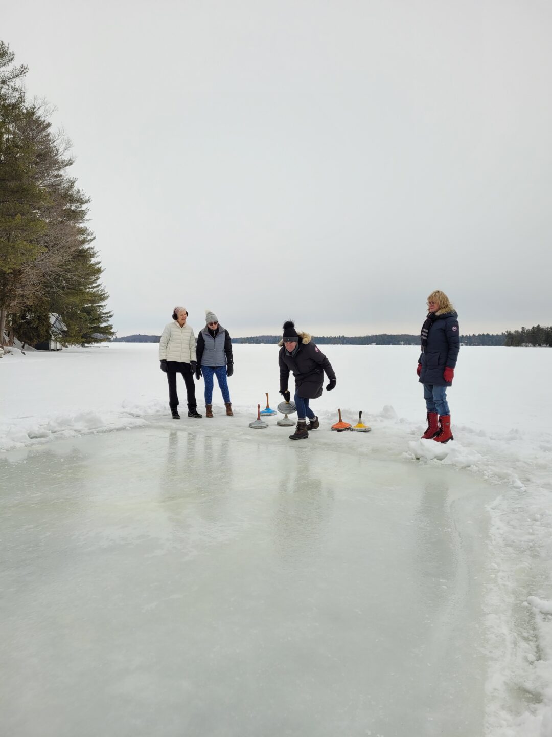 a group of adults playing ice stock sport outdoors on a frozen lake
