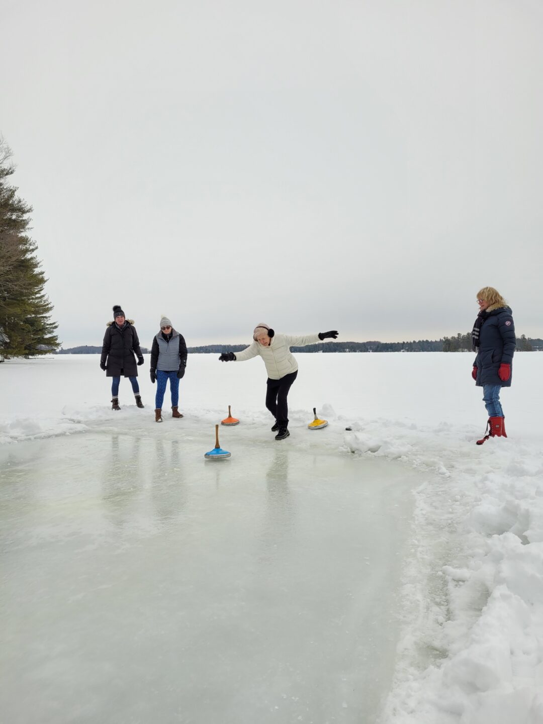 a group of adults playing ice stock sport outdoors on a frozen lake
