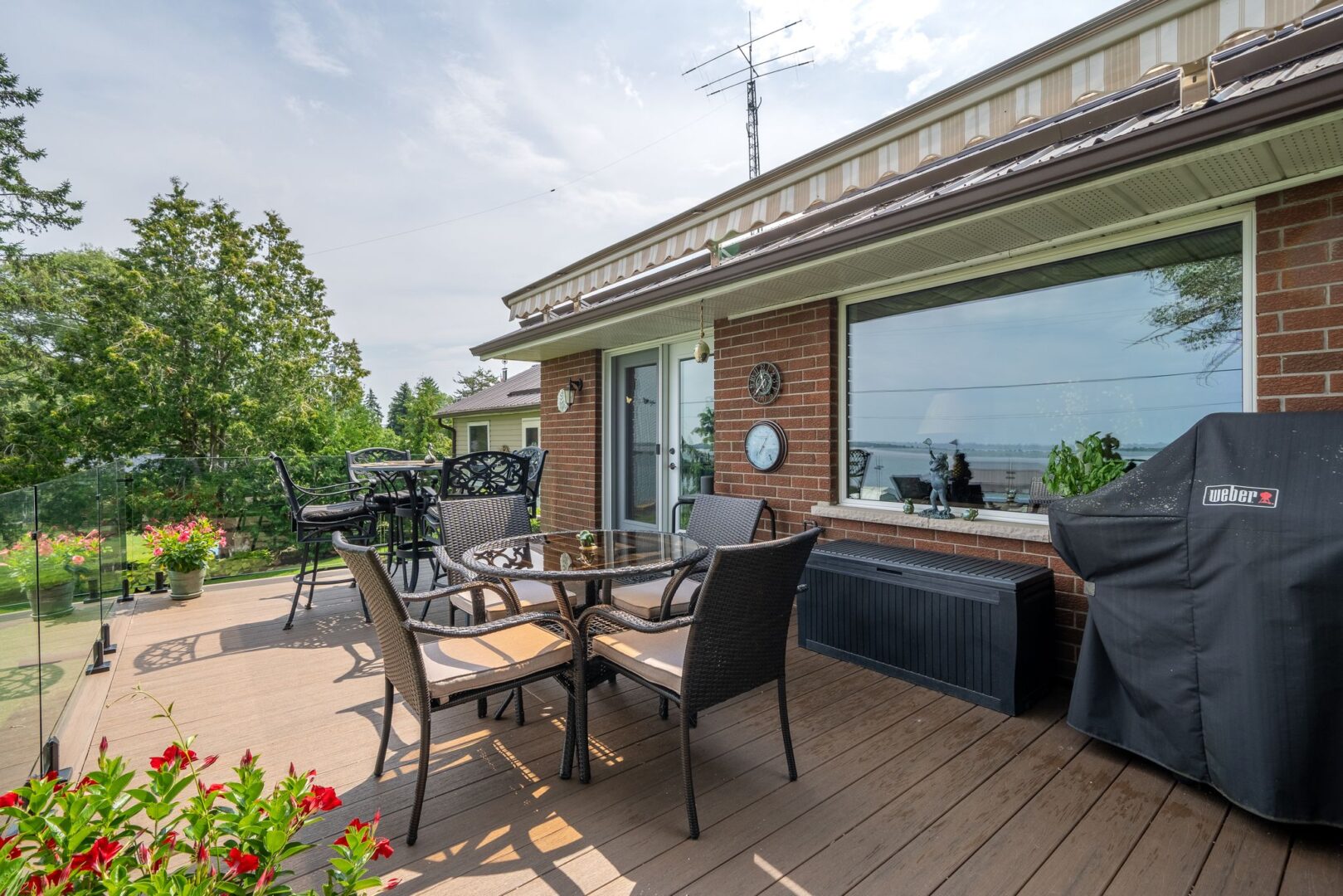 A big deck with a table, chairs, and a barbecue extends off the back of a bungalow.