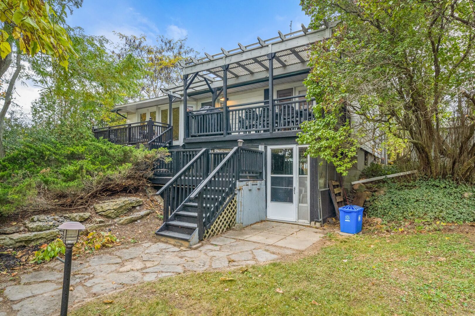 The front of a raised bungalow with stairs leading up to a dark-grey painted porch and the main entrance of the house.