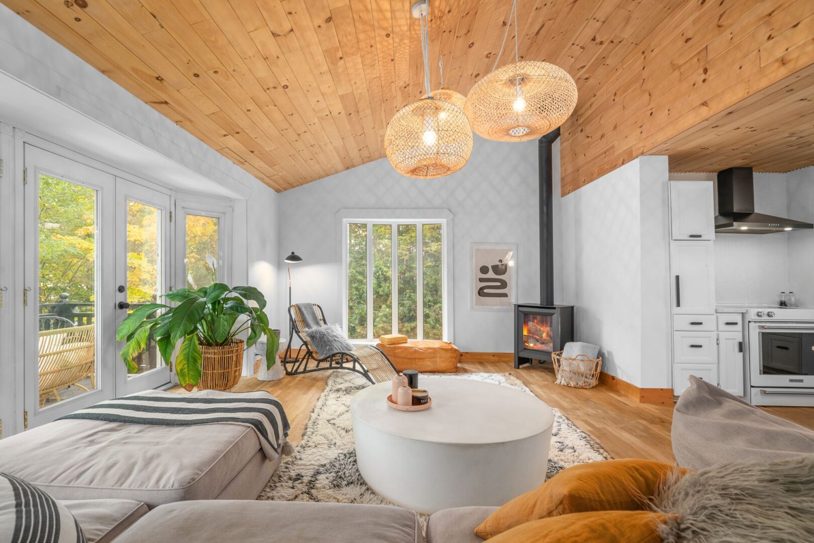 A bright, modern interior of a living area with wood-panelled ceilings and white and light grey furniture.