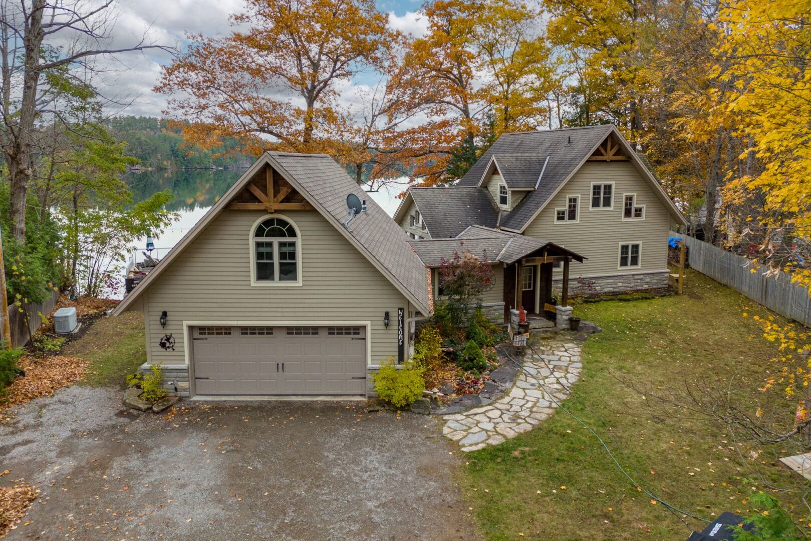 The front of a large cottage with an attached garage and a wide driveway.