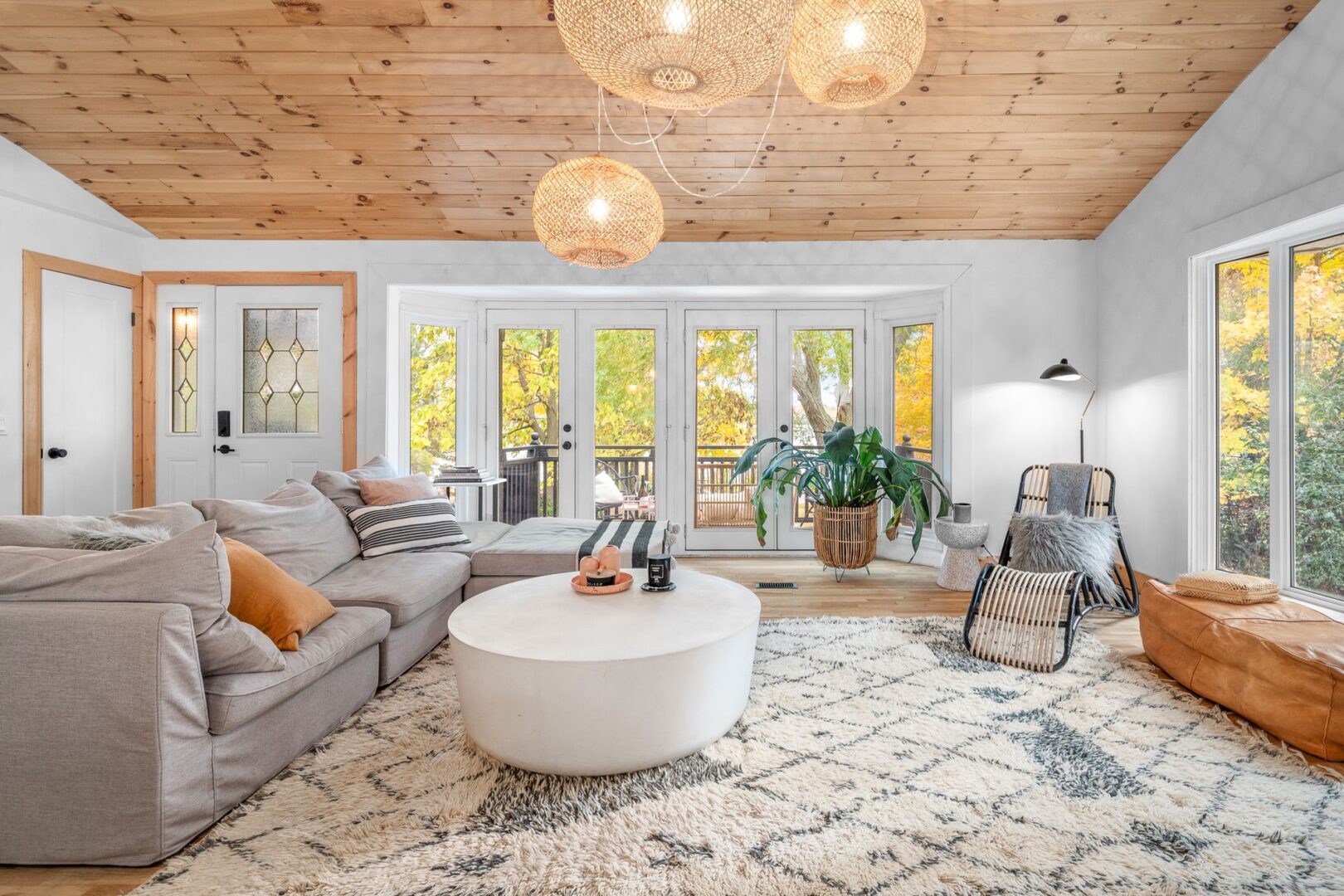 A bright, modern interior of a living area with wood-panelled ceilings and white and light grey furniture.