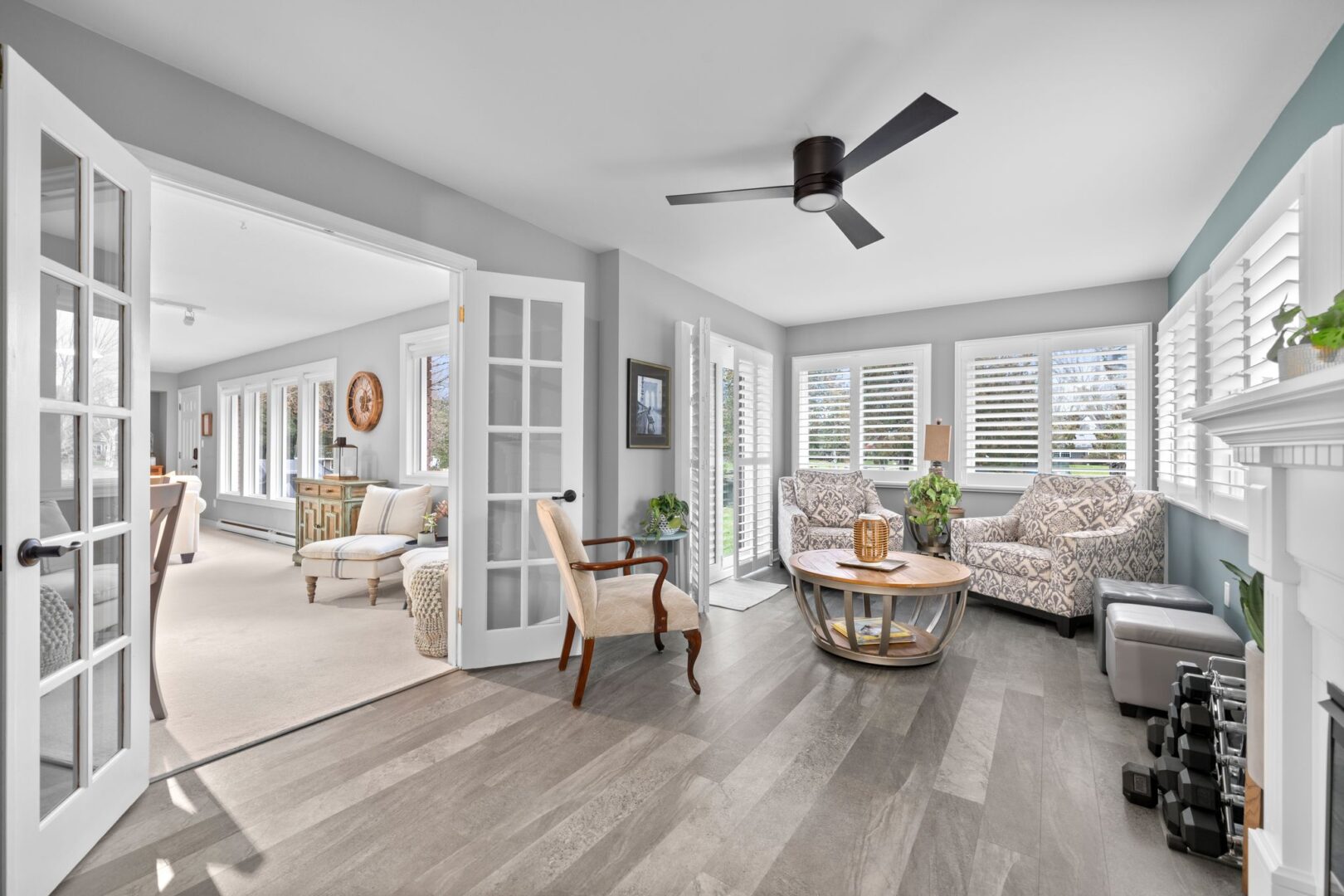 A bright sitting area with chairs, big windows, and grey vinyl plank flooring.