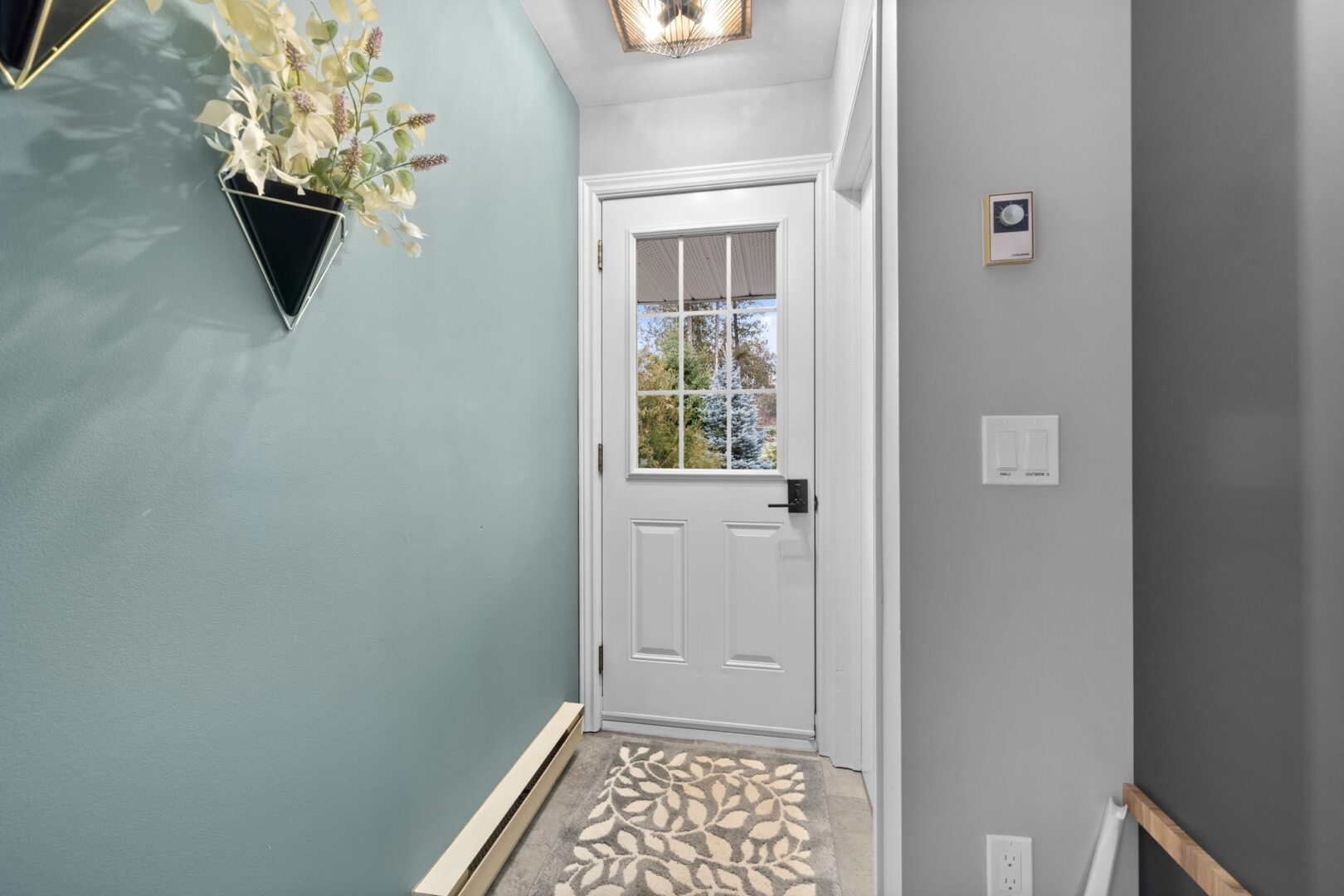 Inside a narrow front entrance of a bungalow, with light blue and grey painted walls.