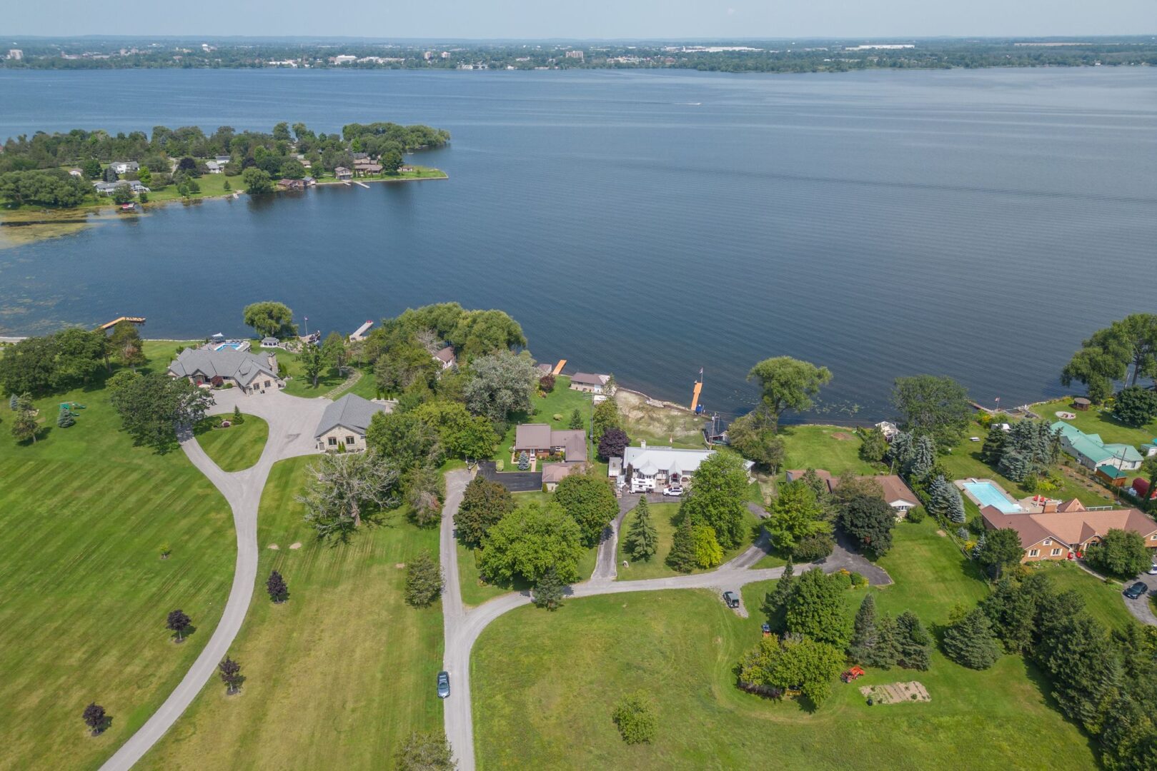 Overhead view of a waterfront area with lots of green space and a few residential properties.