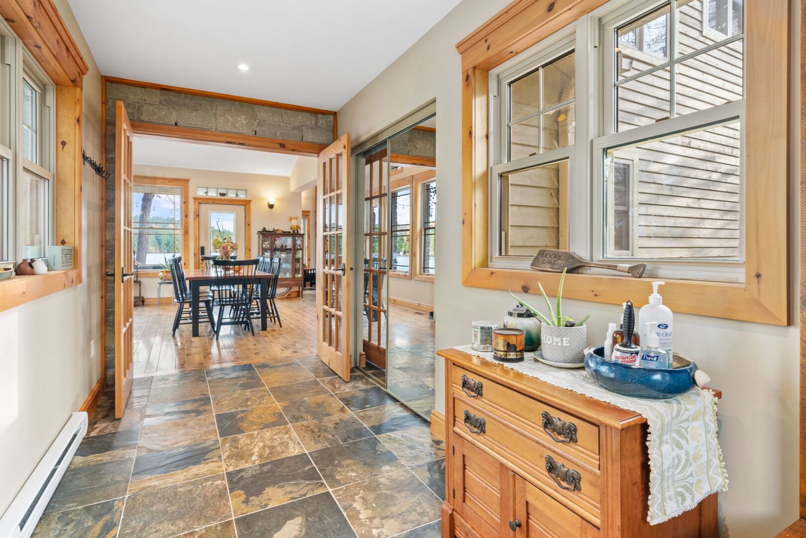 A wide hallway with tile flooring leads into a bright dining space.