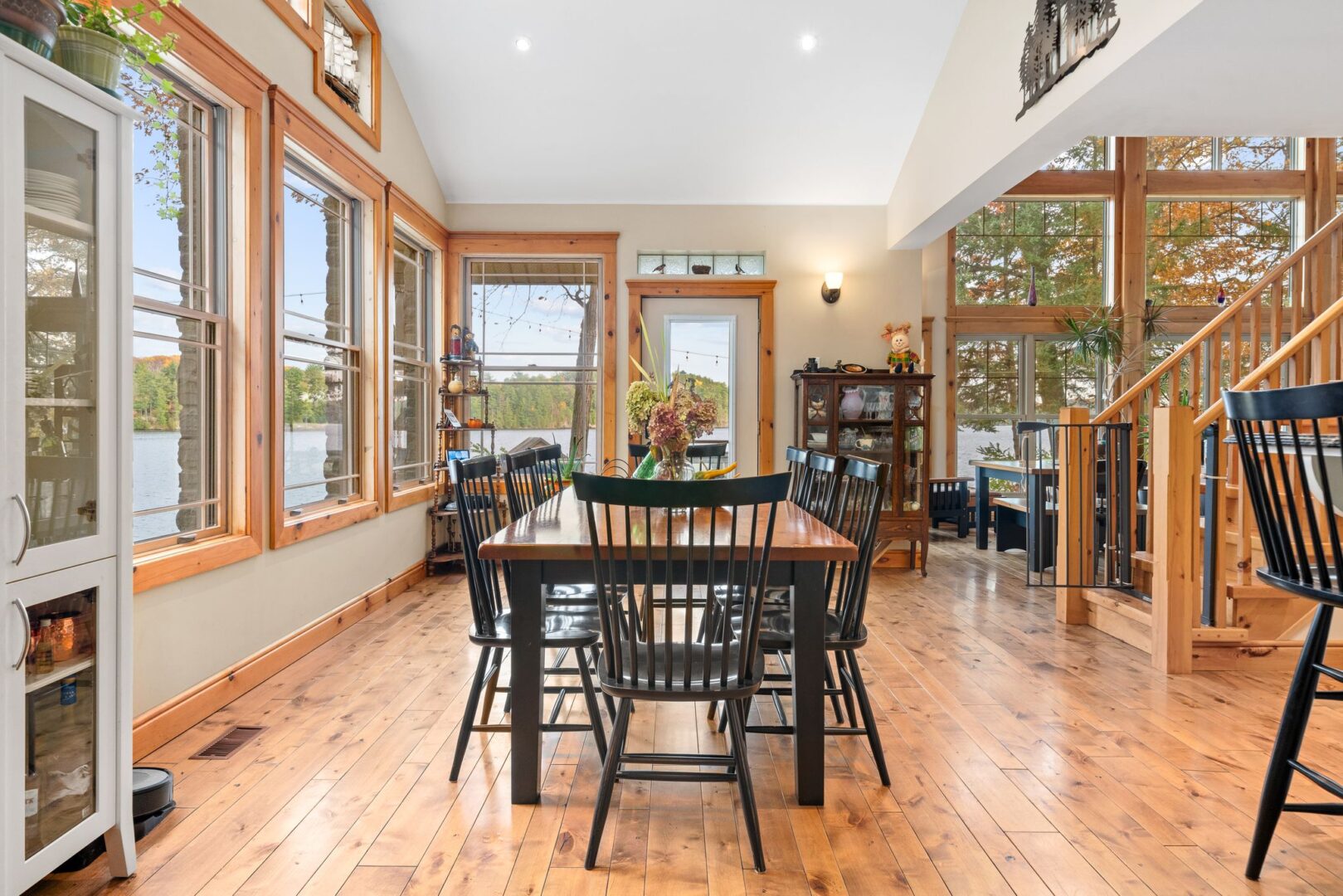 A bright dining area with a table and chairs, lots of windows, and hardwood flooring.