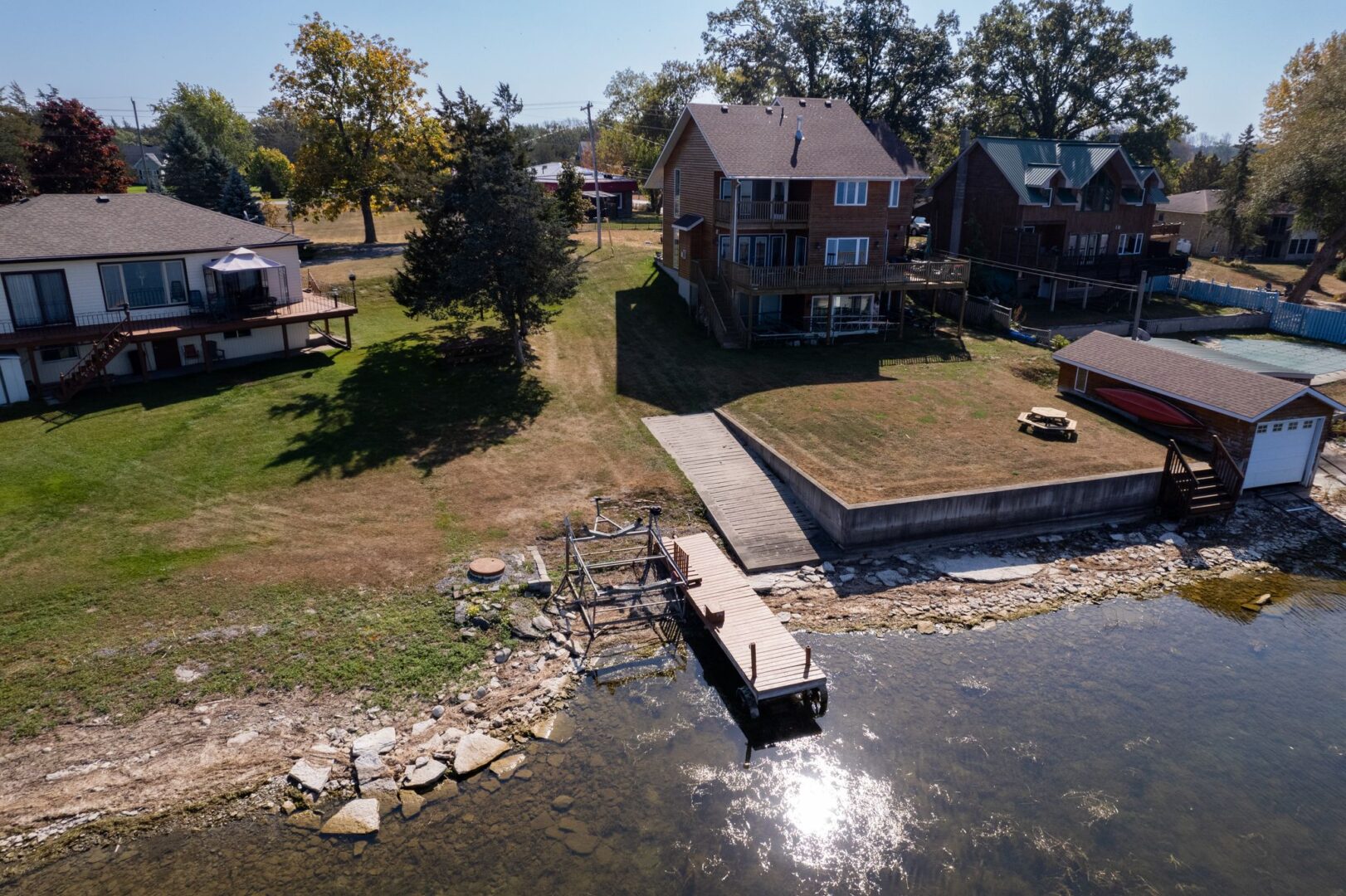 A small dock extends into the water on the shoreline of a residential area.
