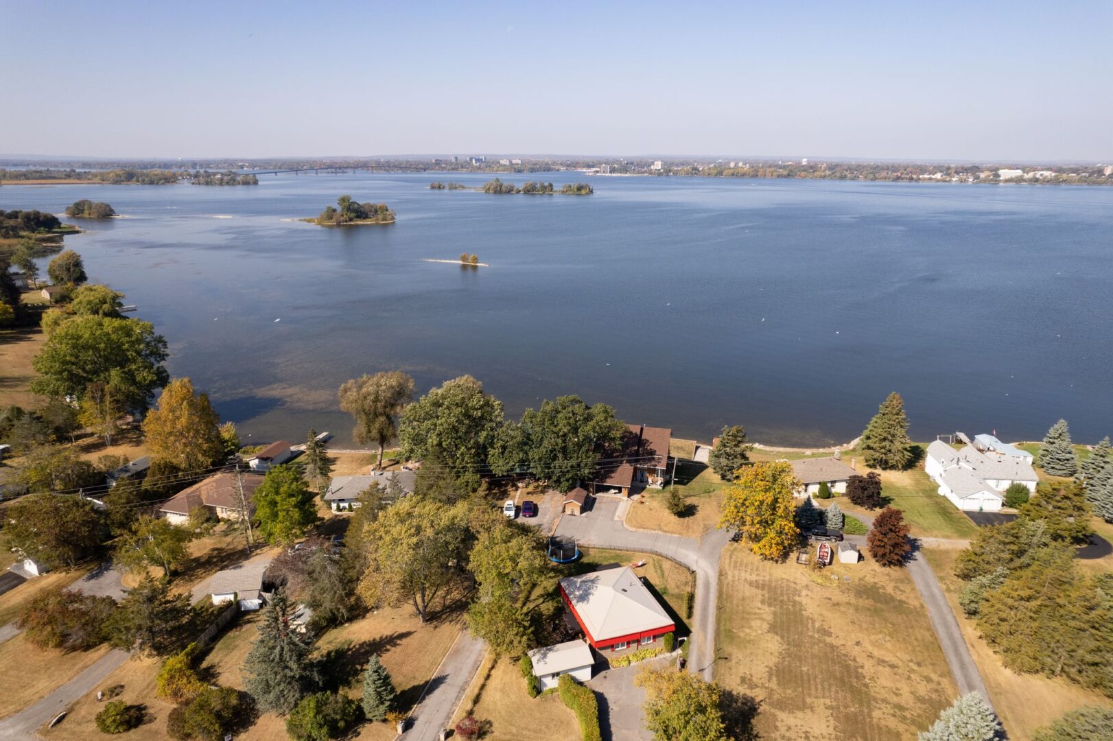 Overhead view of a bungalow property facing out toward the Bay of Quinte, slightly inland. Other properties line the shore.