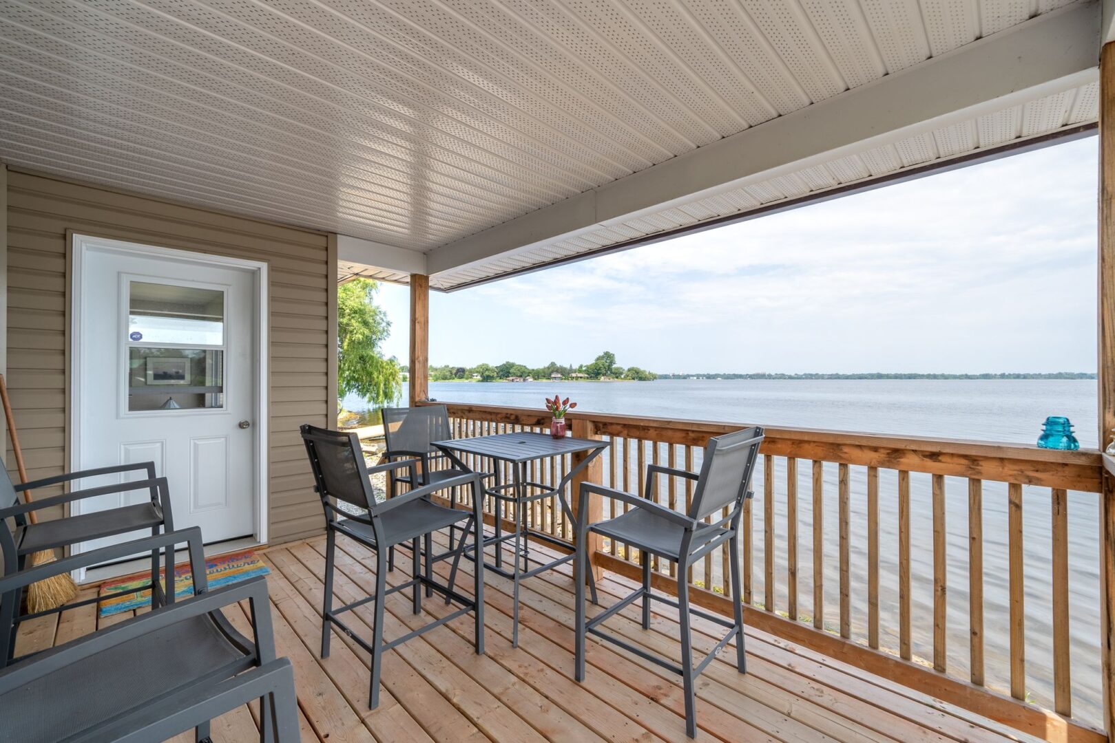 A covered deck with a table and chairs extends off the back of a waterfront bunkie.