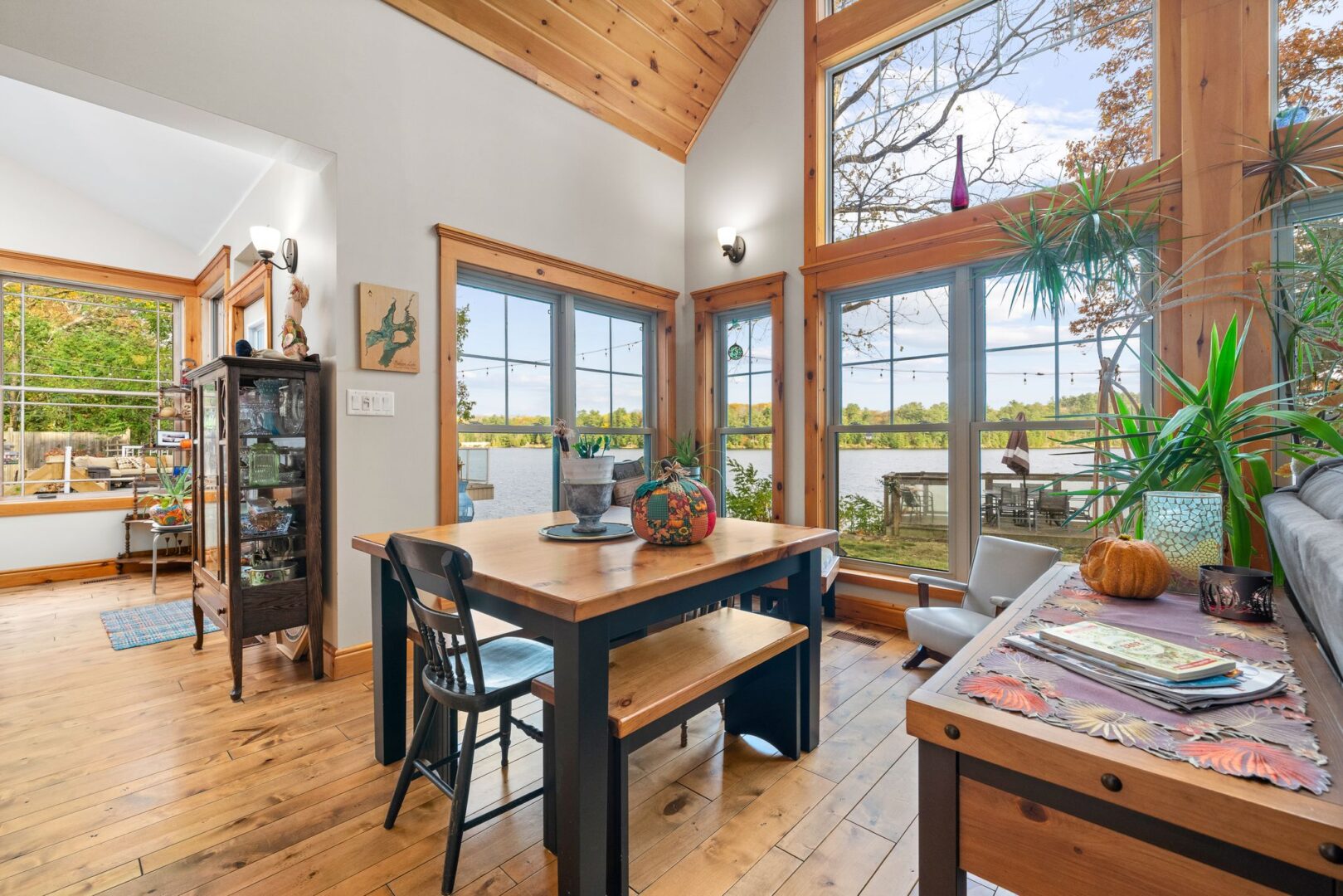 A bright living area with hardwood floors, floor-to-ceiling windows, and a small desk.