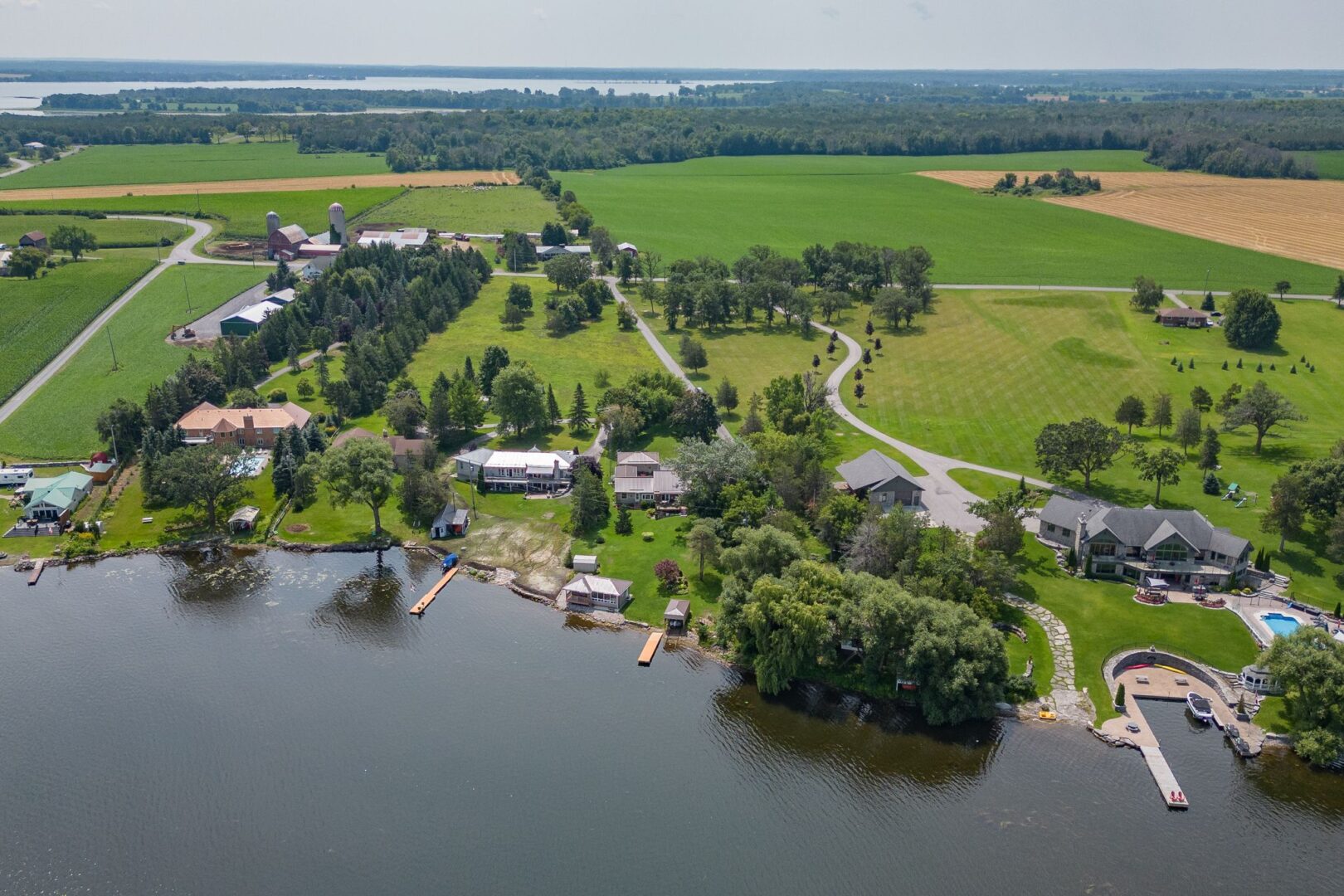 Overhead view of a waterfront area with lots of green space and a few residential properties.