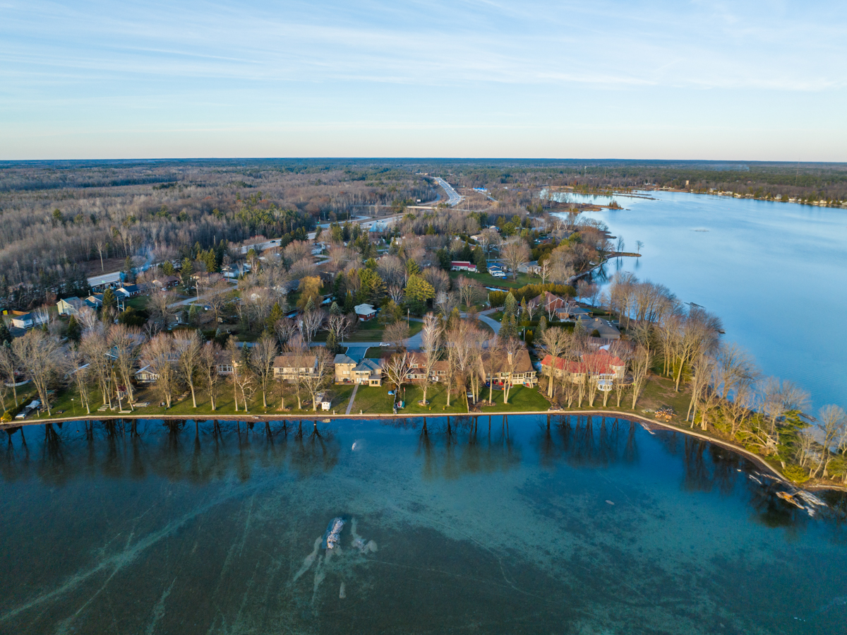 Overhead view of a residential area that backs onto a lake. Waterfront properties line the shore.