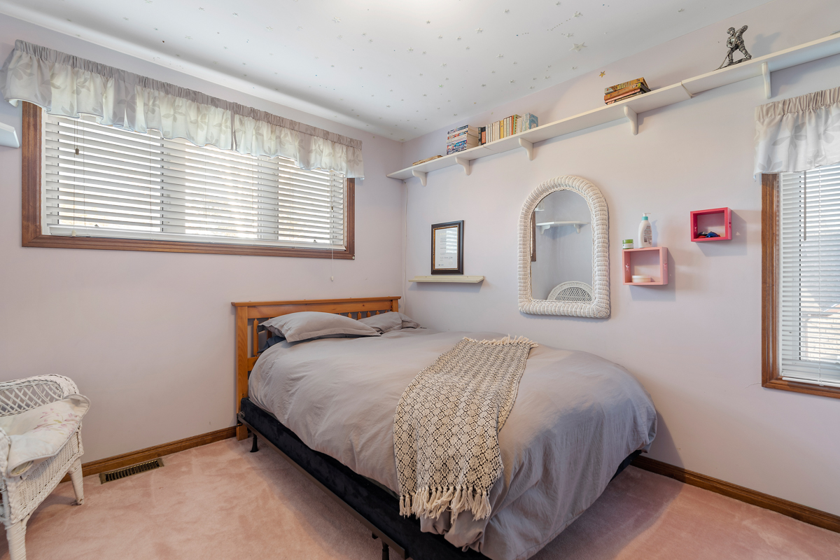A bedroom with pink carpet flooring and a double bed.