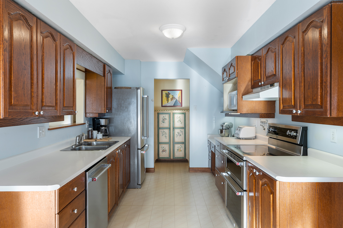 An updated kitchen with brown cupboards and stainless steel appliances.