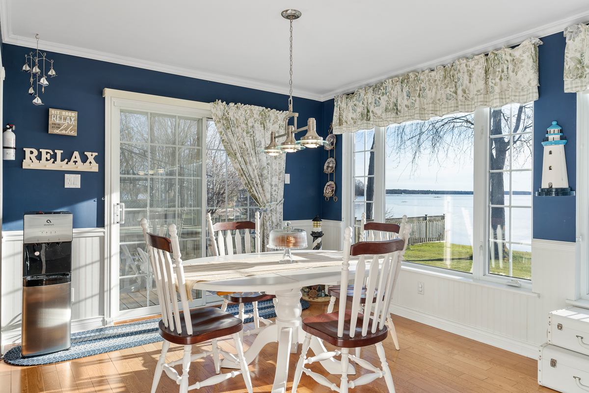 A bright dining area with plenty of windows, navy blue accents, and a white table and chairs.
