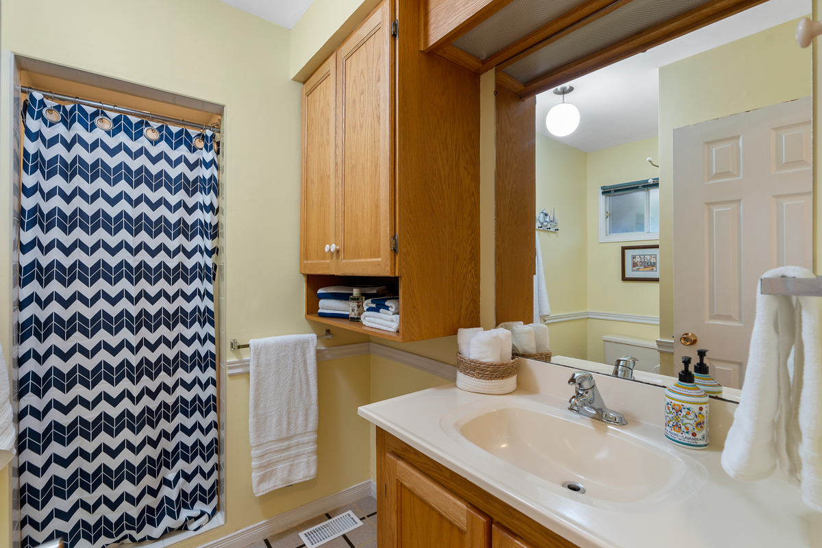 A small three-piece bathroom with a toilet, a sink, a walk-in shower, and tile flooring.