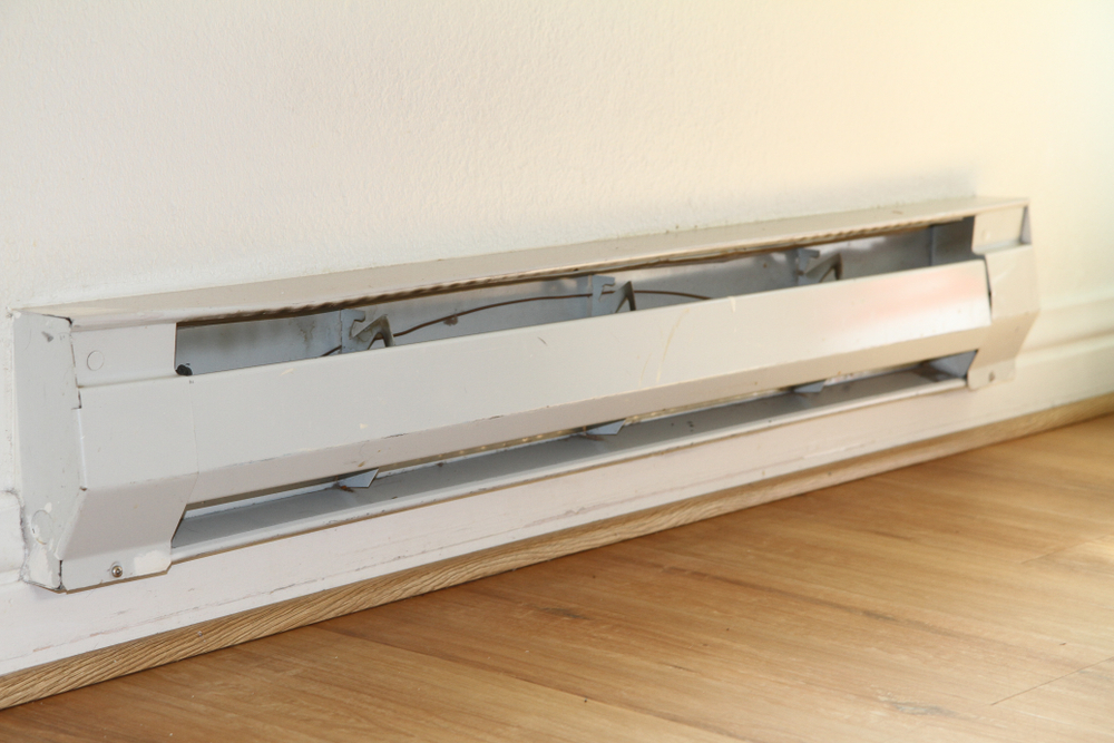 A beige baseboard heater against a white wall
