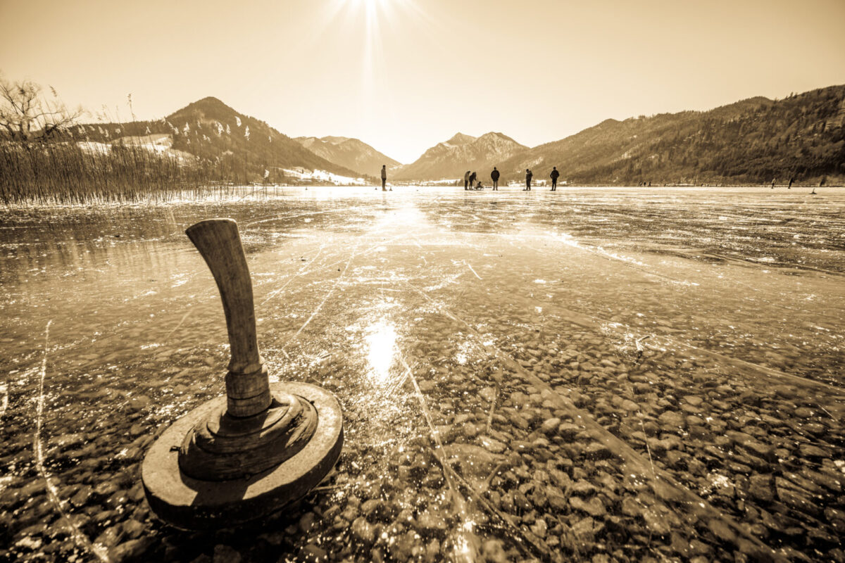 an ice stock paddle on a frozen lake with mountains in the background