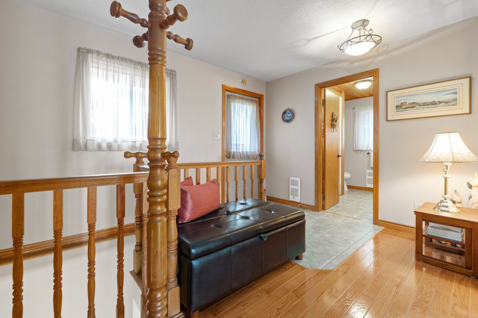 Inside the front entrance of a large waterfront bungalow, with hardwood floors, a wood coat rack, and wood-trimmed doorframes.