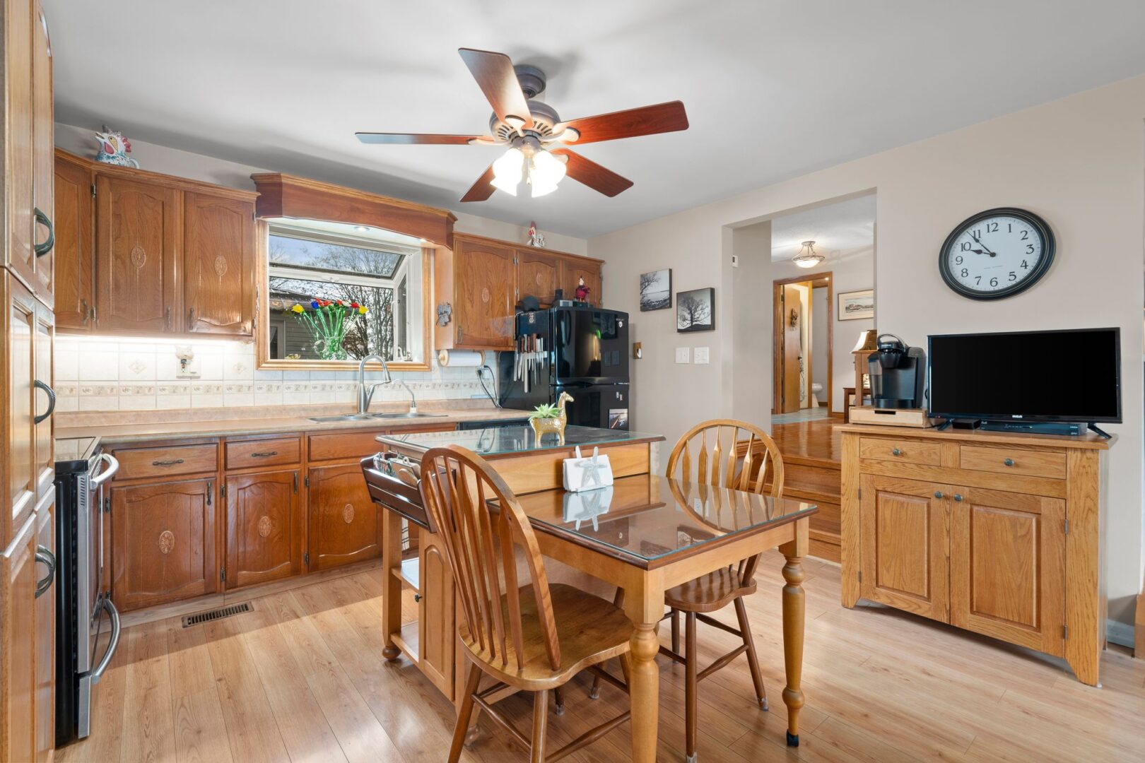 A kitchen with wooden cupboards, hardwood flooring, and a small table and chairs next to an island.